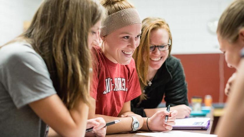 Group of smiling students working on class project at table